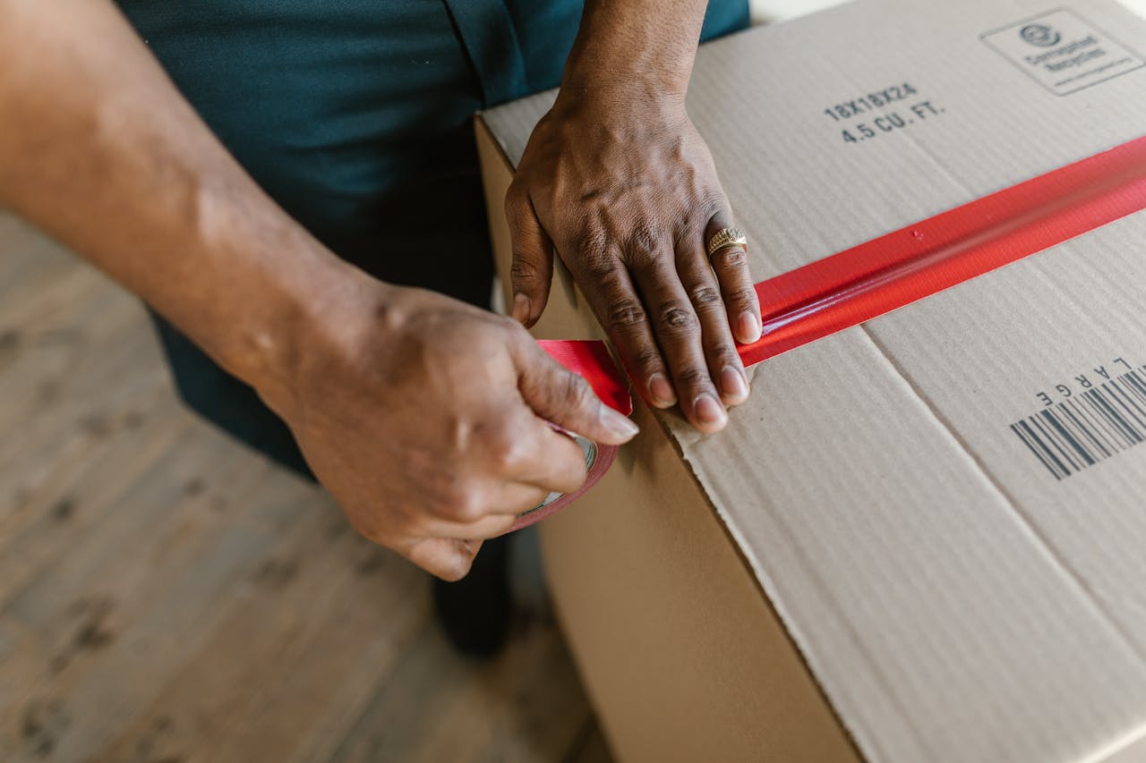 Close-Up Shot of a Person Putting Tape on a Cardboard Box